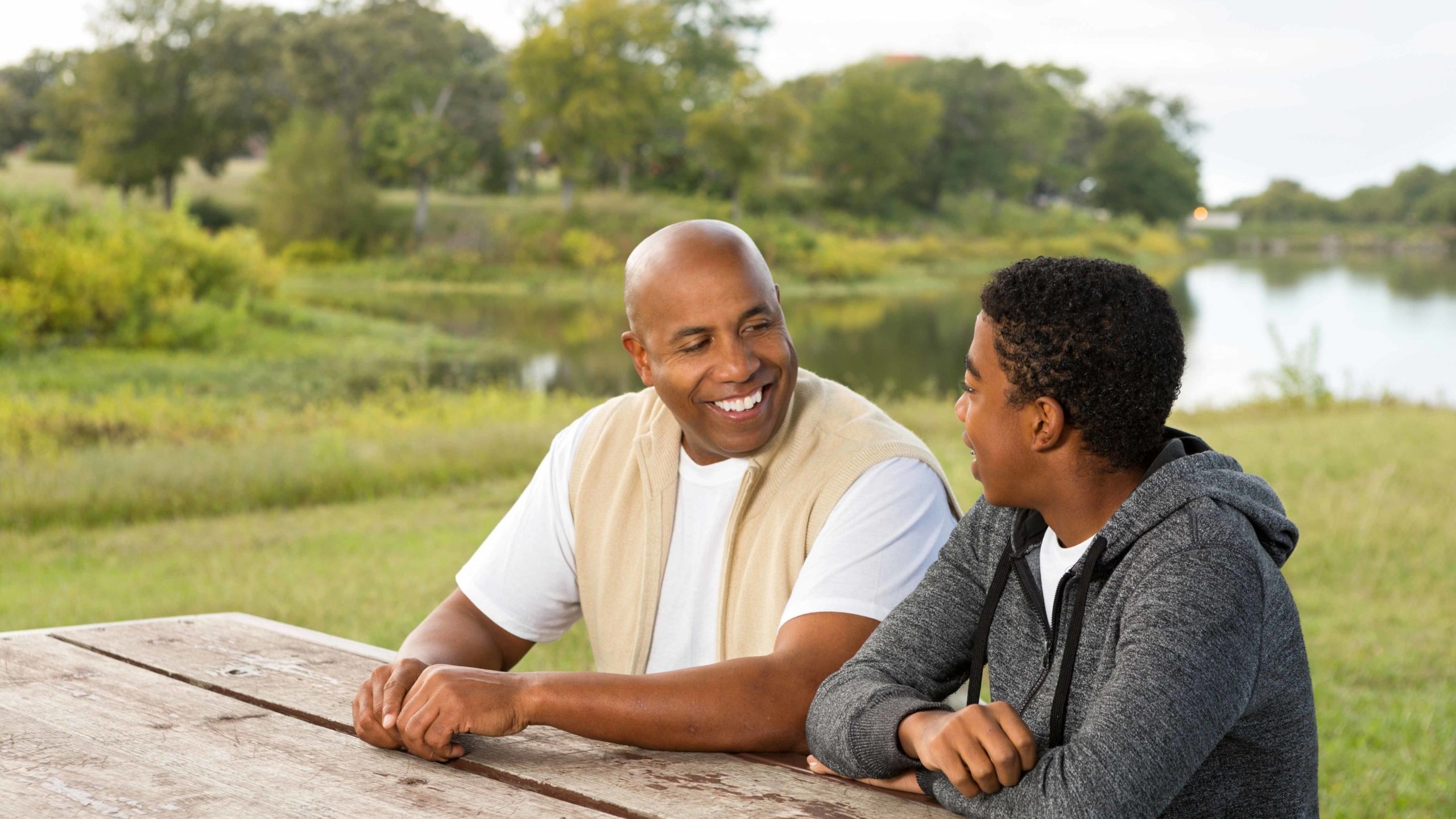 Father and teenage son have a conversation in a park.
