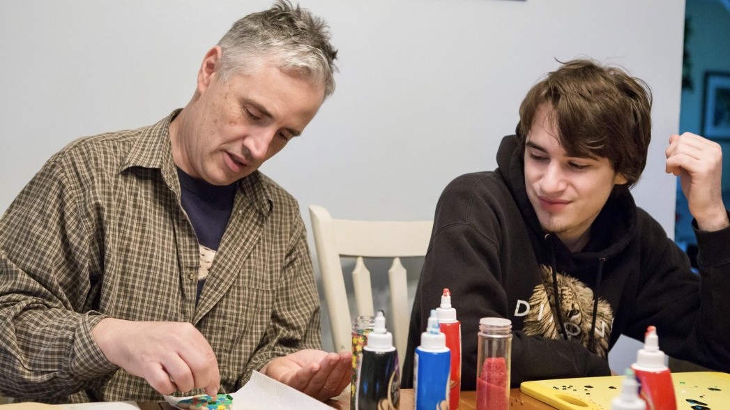 Father and Teenage Son work together on cookie decorating.