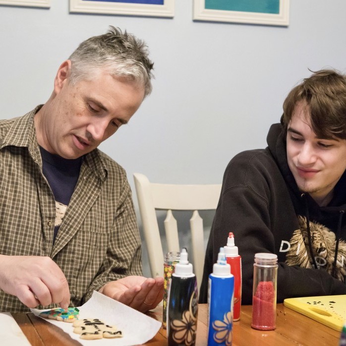 Father and Teenage Son work together on cookie decorating.